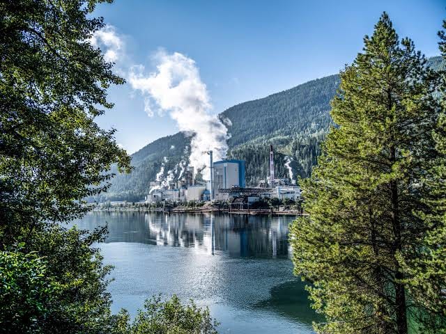 A British Columbia pulp-and-paper mill venting steam beside a lake